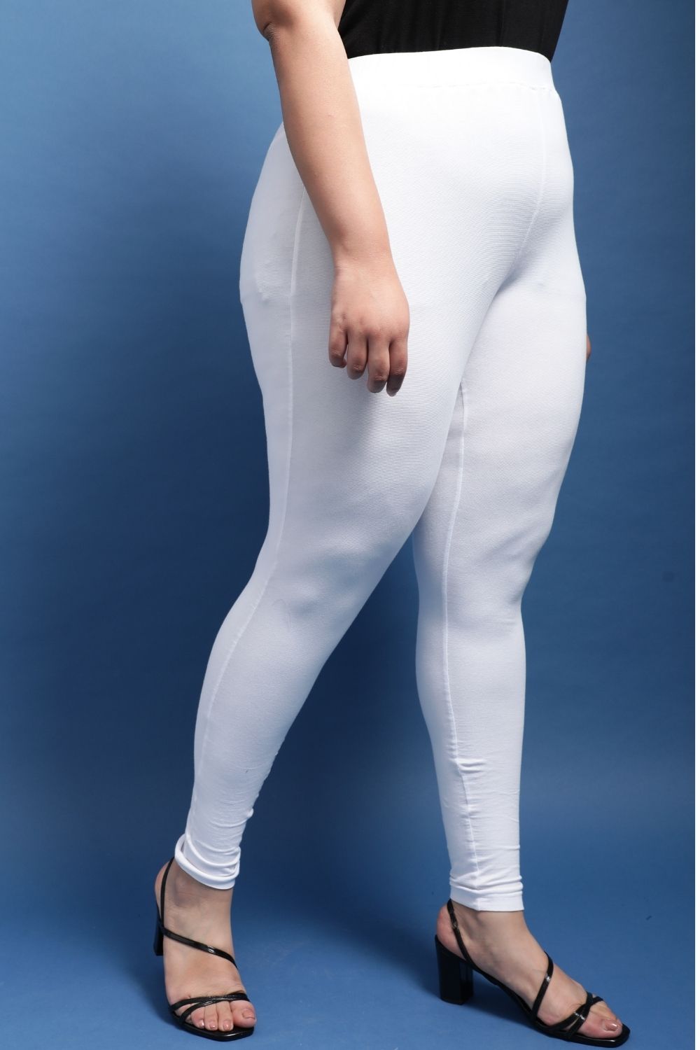 Front view a woman in white leggings with a black top and black shoes.