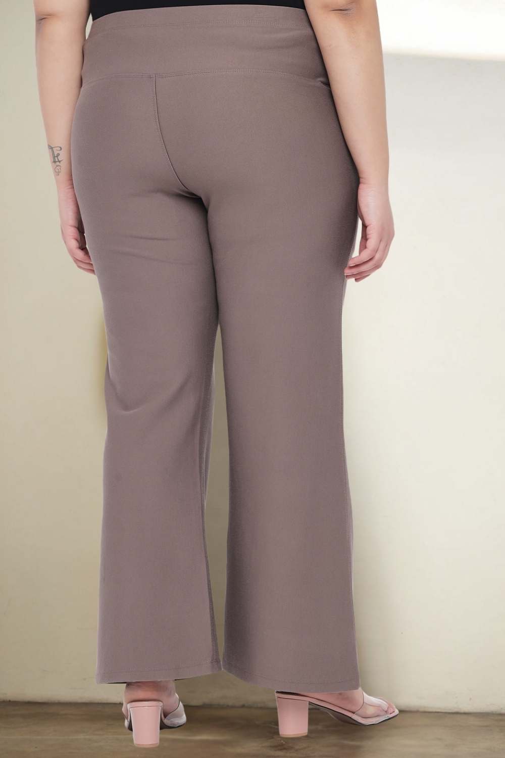 Side view a woman in a black top and grey pants.
