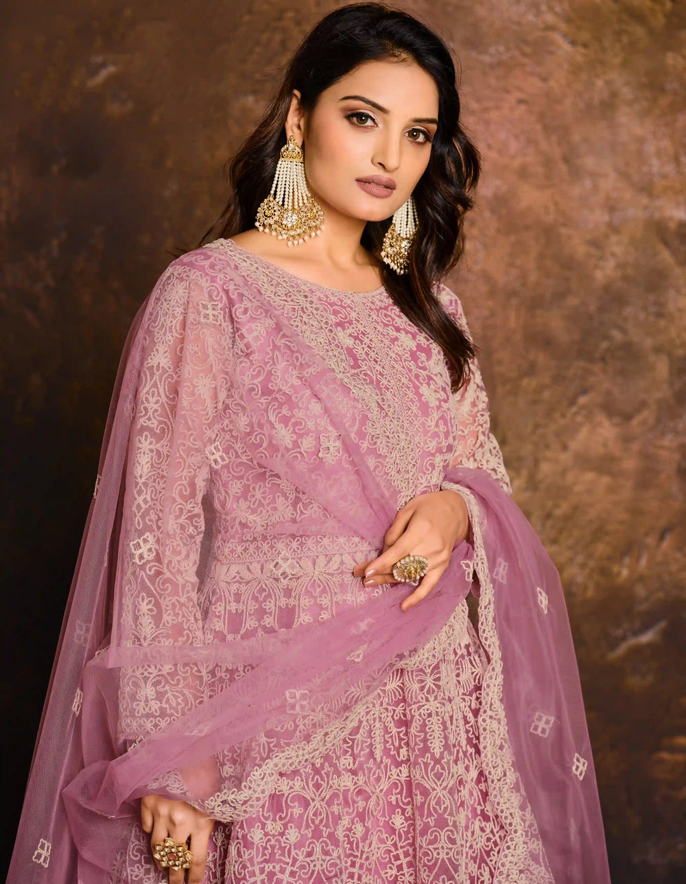 Detail view a model in a pink Anarkali suit with a white blouse and a pink.